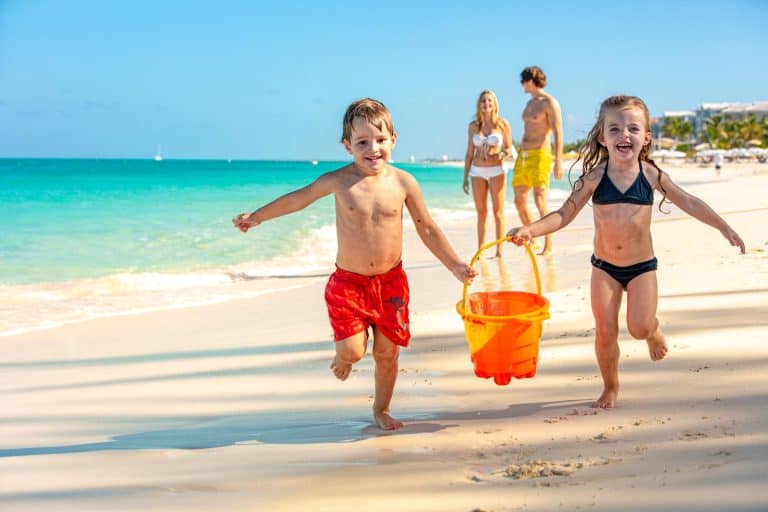 Children running on beach with parents in background